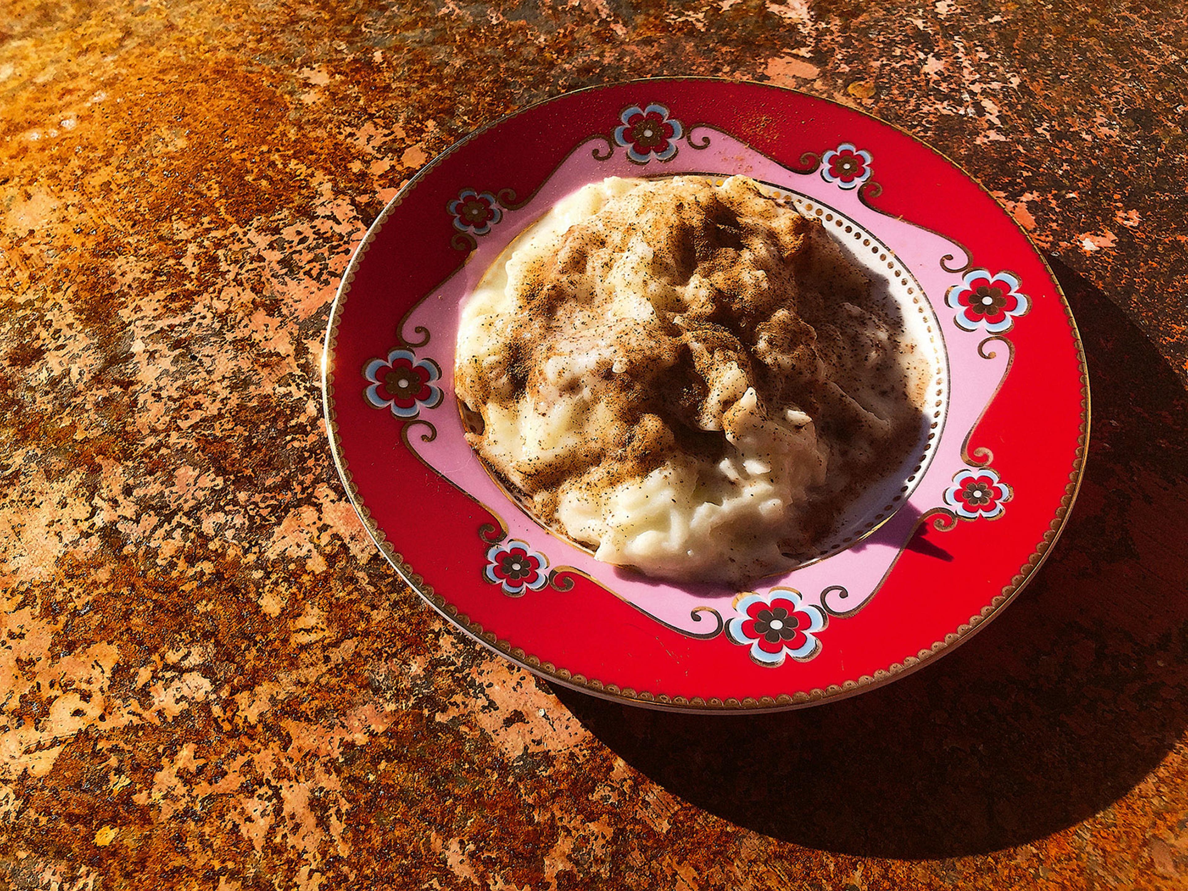 Rivet äpple med yoghurt och kanel på ett rött, blommigt fat