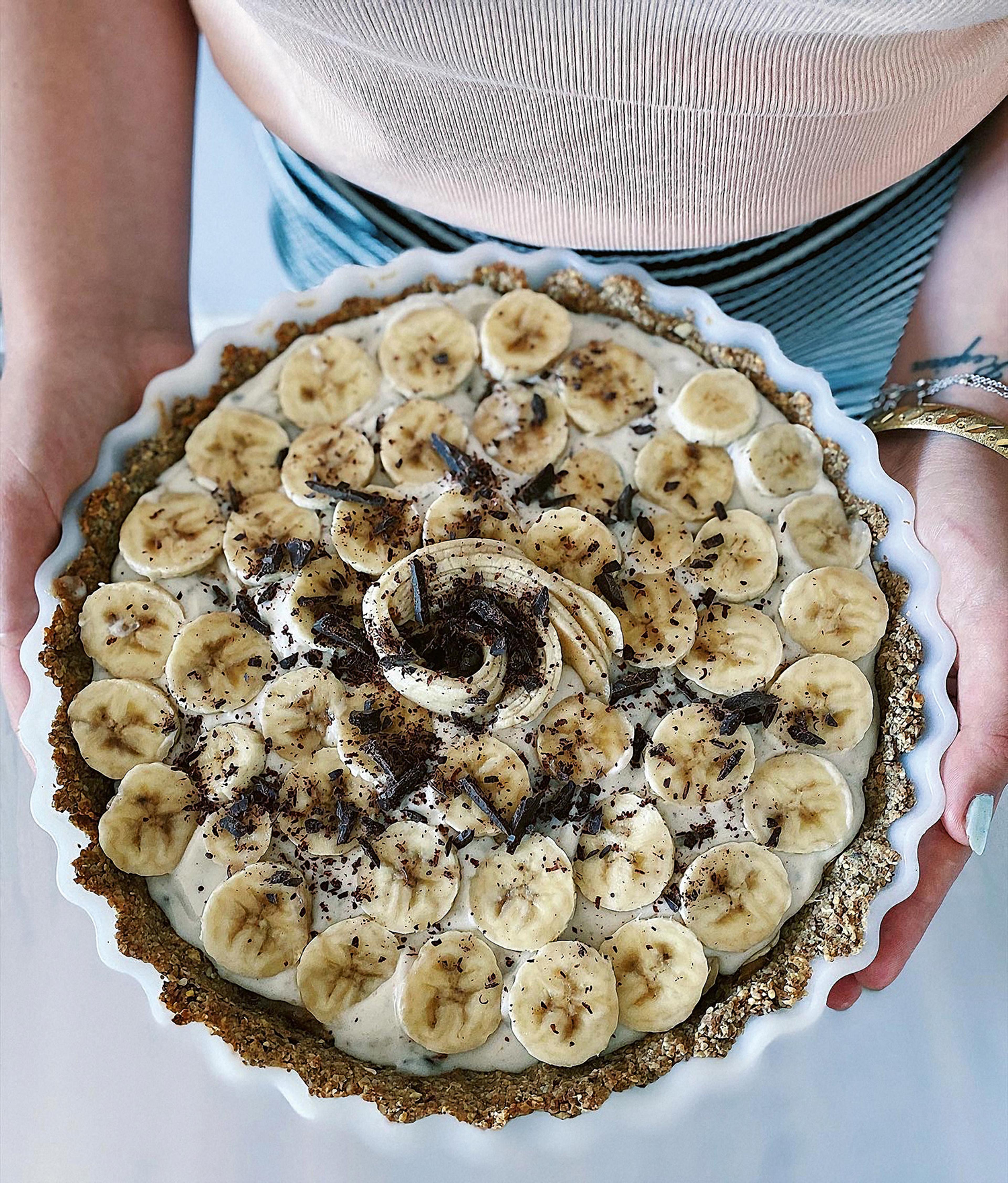 Banoffepaj toppad med bananskivor och riven choklad i en vit pajform