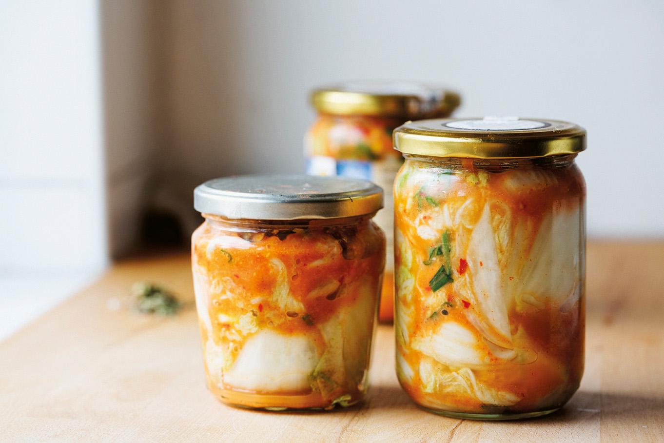 Glasburkar med hemgjord kimchi på ett träbord