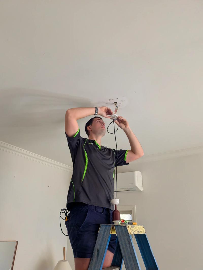 Electrician fitting an LED downlight into a ceiling