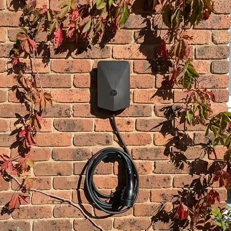 Home EV charger mounted on a wall beside a garage