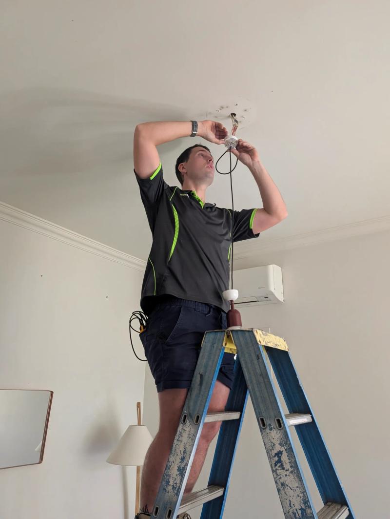 Electrician fitting a downlight in a bungalow ceiling