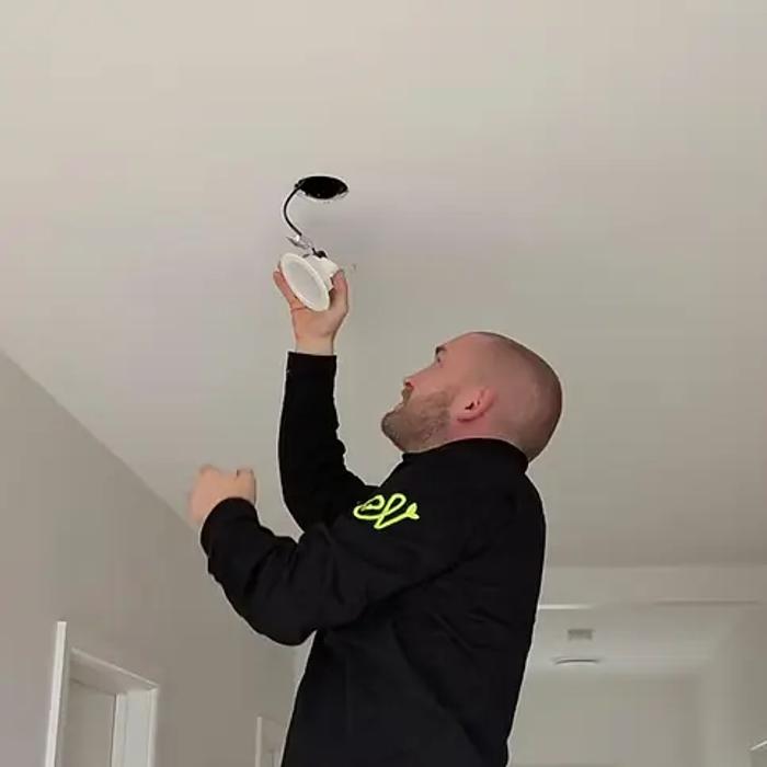 Revelectrical electrician fitting an LED downlight into a ceiling