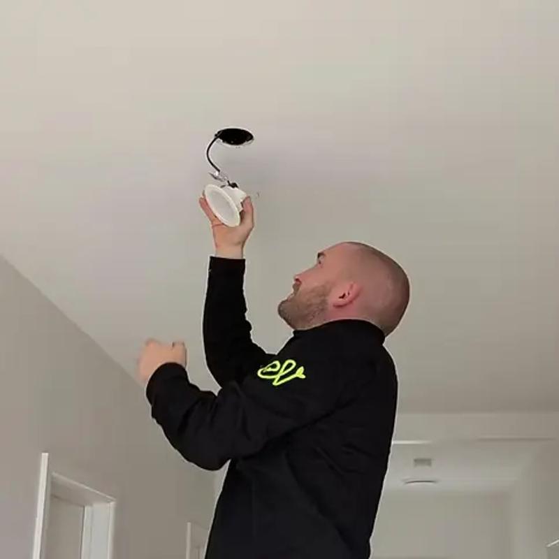 Revelectrical electrician fitting an LED downlight into a ceiling