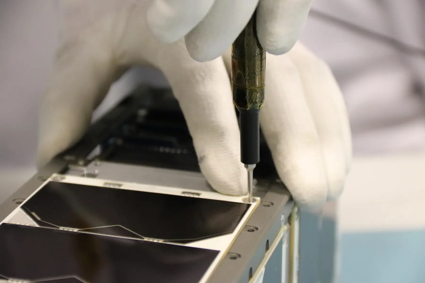 Picture of a person screwdriving a satellite panel. 