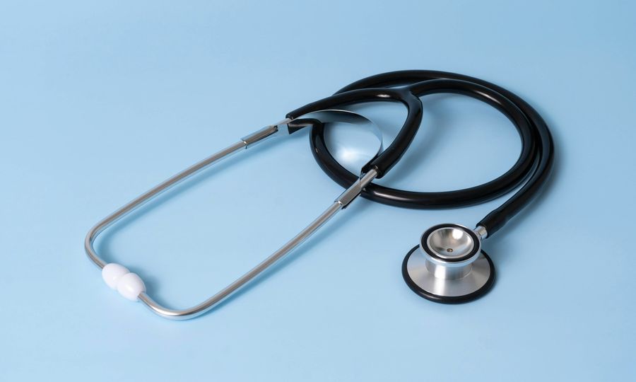 A black medical stethoscope with silver chest piece on a light blue background