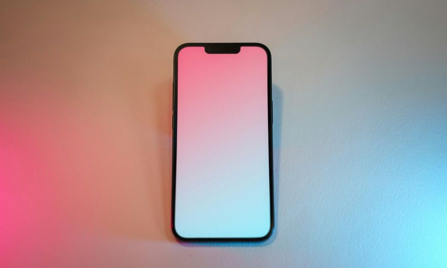 A pink and white cell phone sitting on top of a table