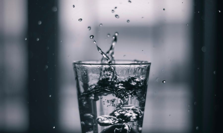 Water pouring on clear drinking glass