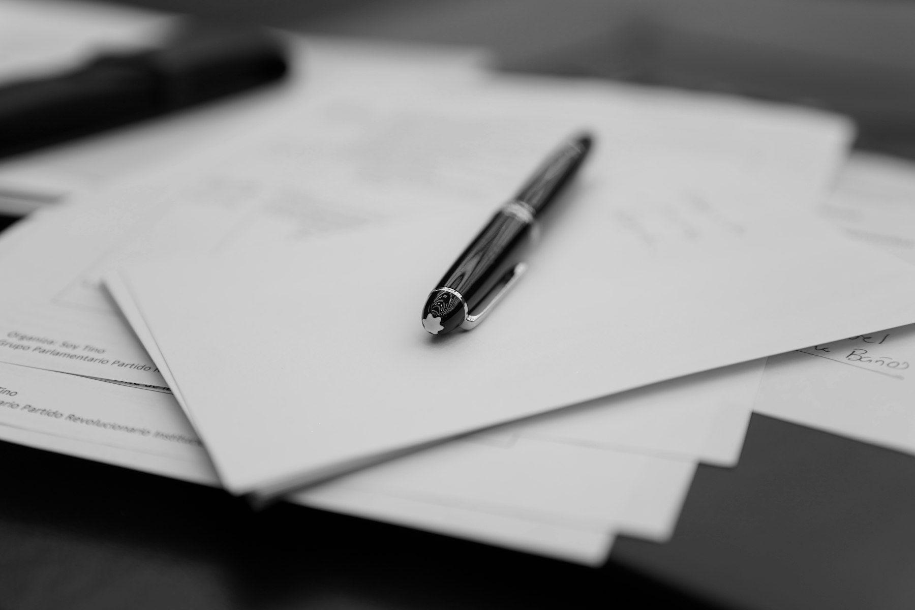 A pen sitting on top of a pile of papers