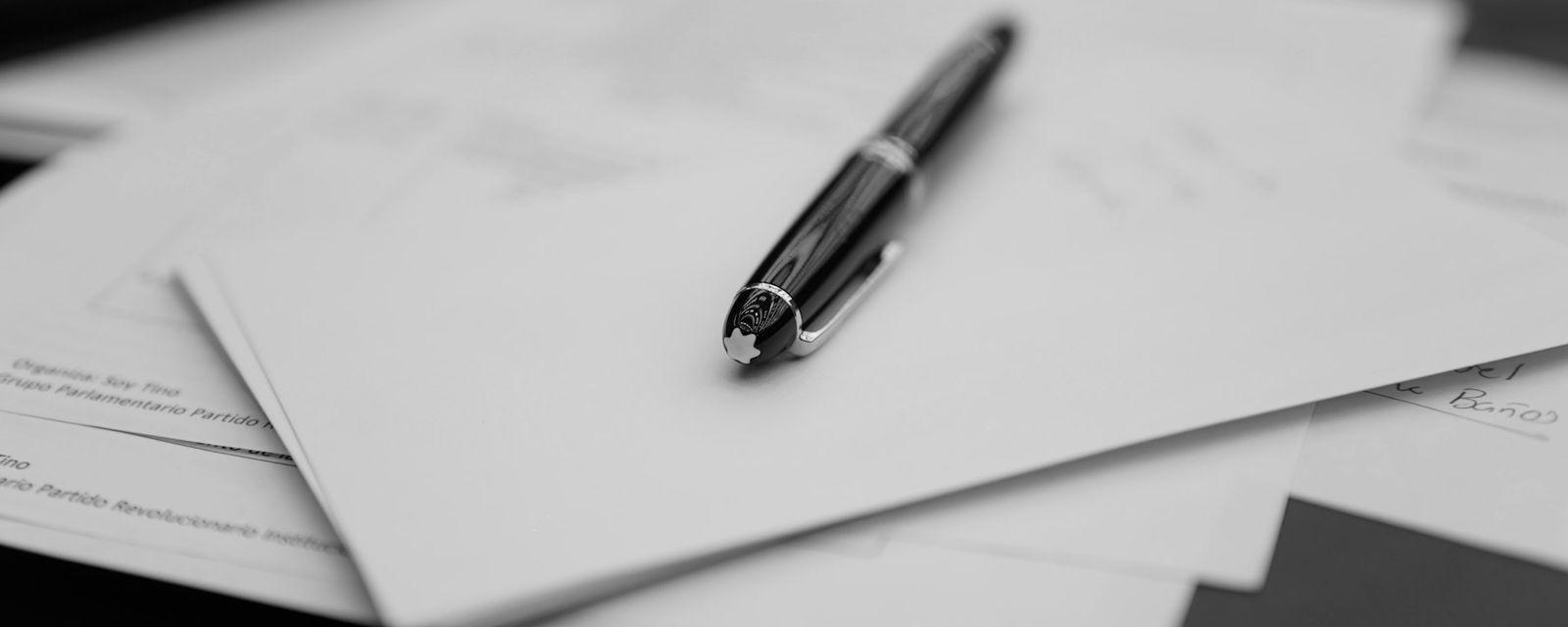 A pen sitting on top of a pile of papers