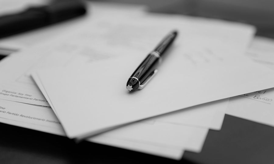 A pen sitting on top of a pile of papers
