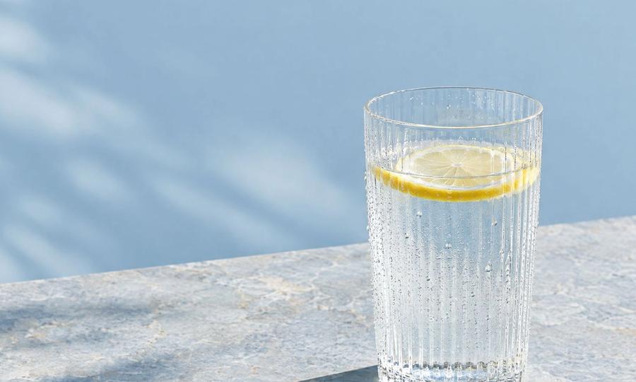 A glass of water with a slice of lemon in the sunlight