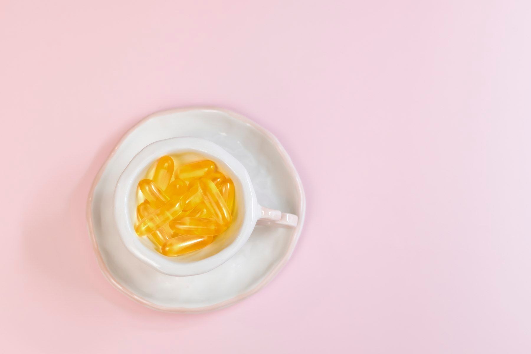 A white bowl filled with yellow liquid on top of a pink surface