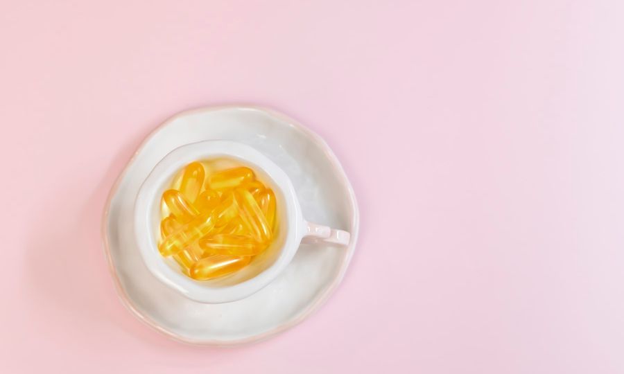 A white bowl filled with yellow liquid on top of a pink surface