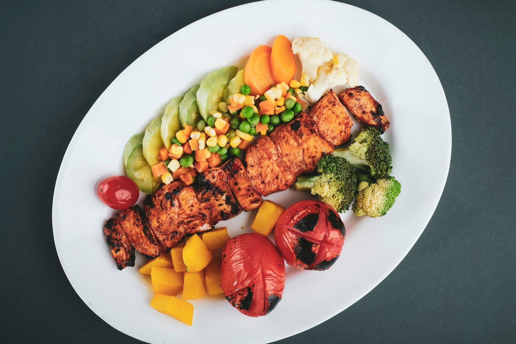 Grilled meat with sliced lemon and sliced tomatoes on white ceramic plate