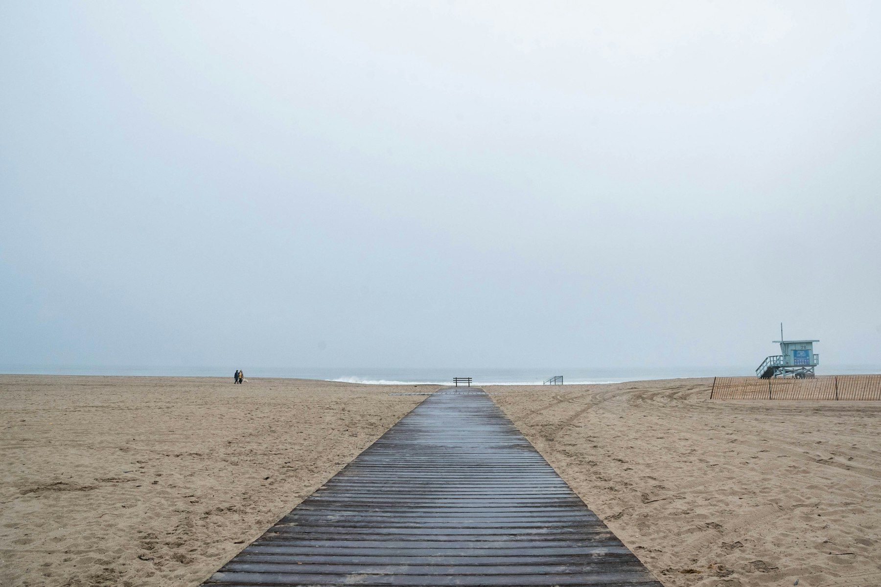 Wooden walkway on a sandy beach with lifeguard tower