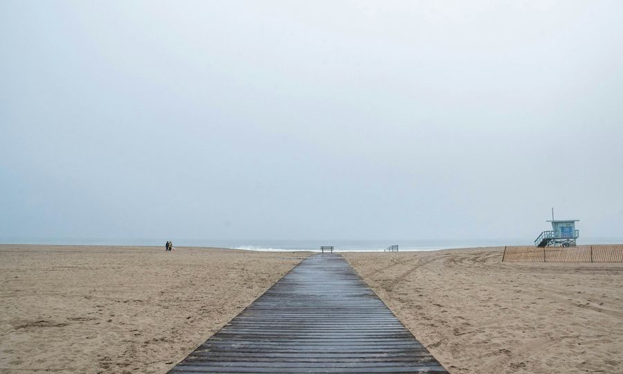 Wooden walkway on a sandy beach with lifeguard tower