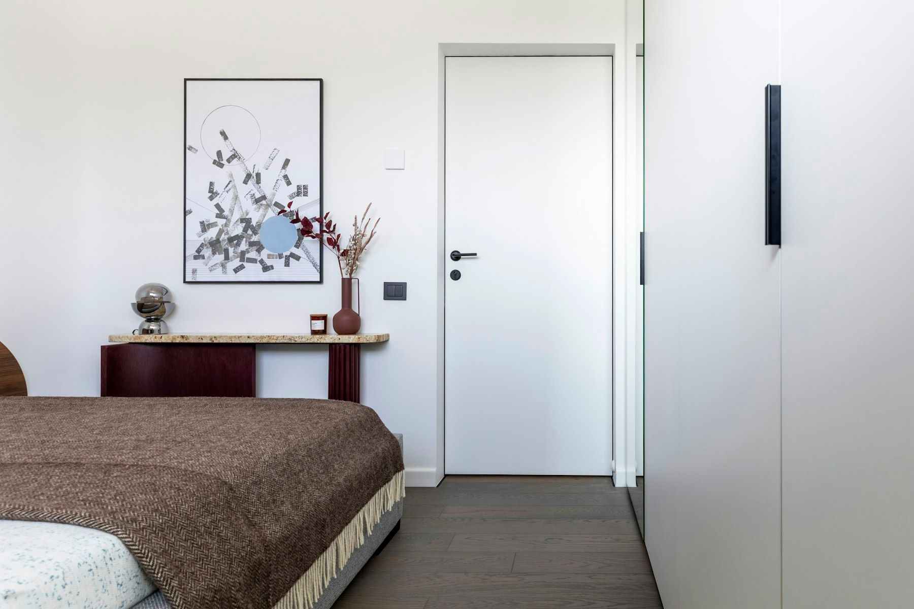 Modern bedroom with bed, artwork, and white wardrobe