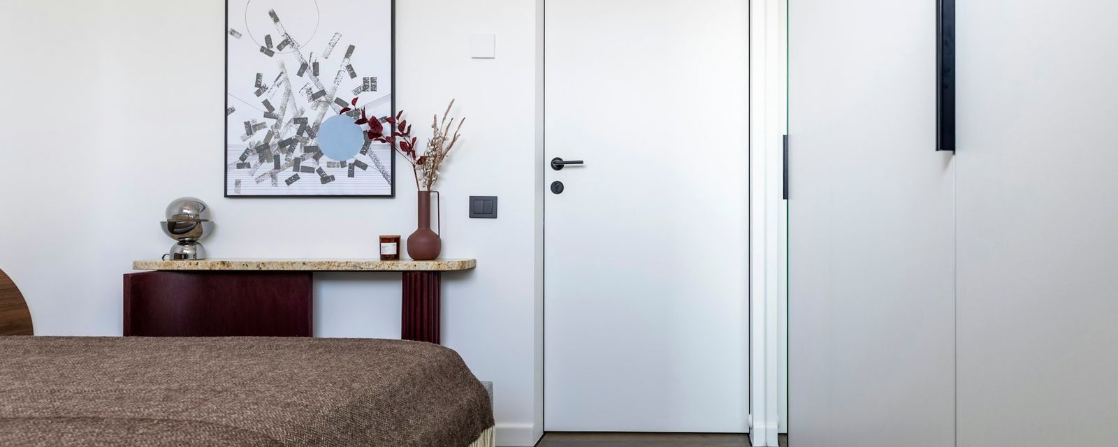 Modern bedroom with bed, artwork, and white wardrobe