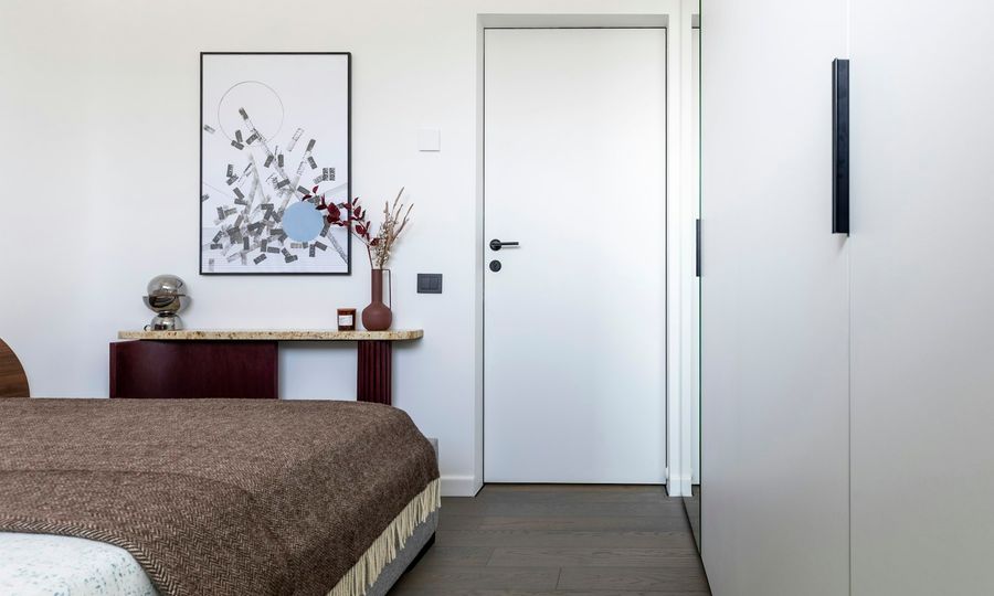 Modern bedroom with bed, artwork, and white wardrobe