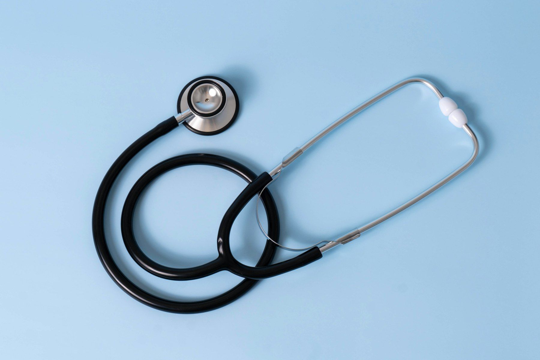 A black medical stethoscope on a light blue background