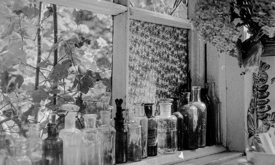 A collection of vintage glass bottles lined up on a window sill with textured glass