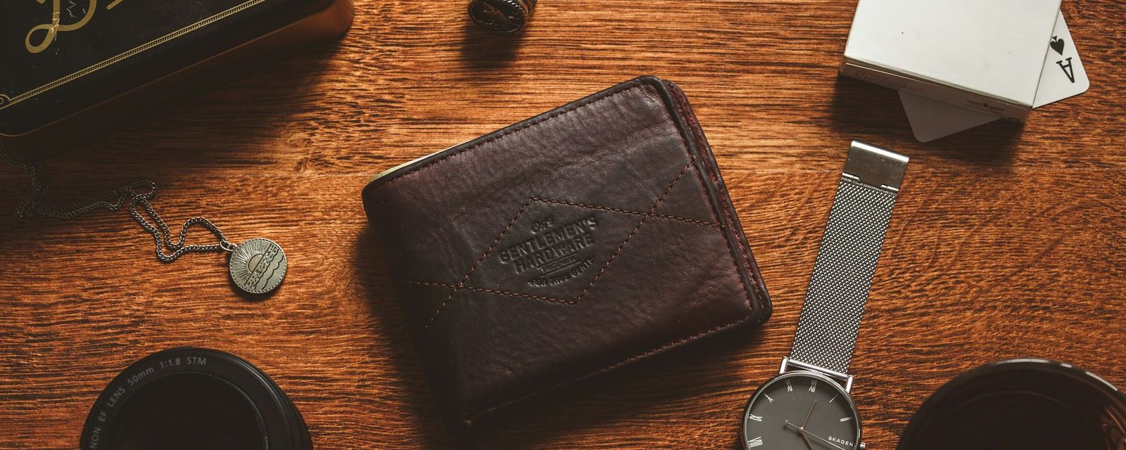A wooden table topped with a wallet and a watch