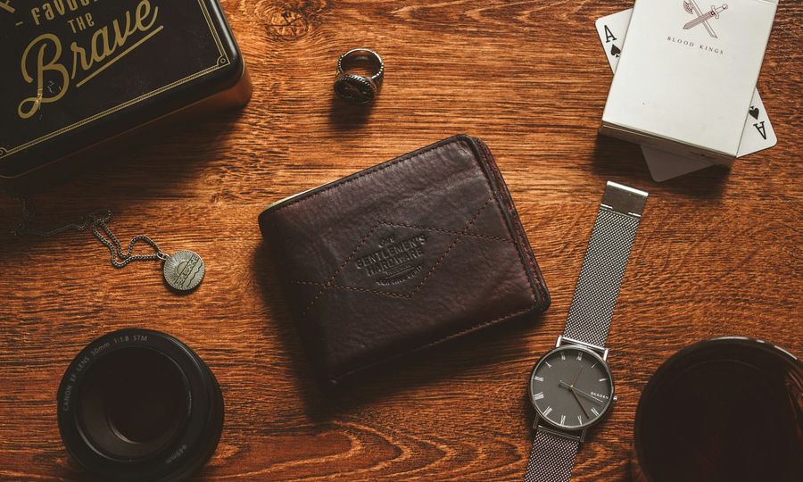 A wooden table topped with a wallet and a watch