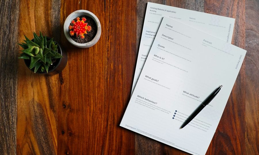 A wooden table topped with papers and a pen
