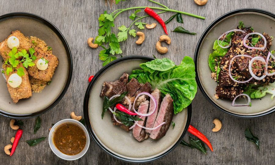 Three plates of asian food on wood table