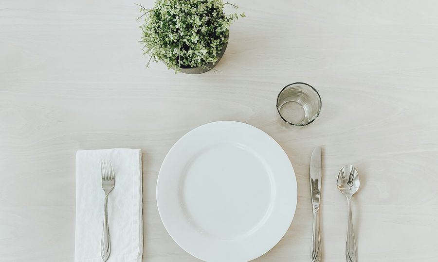 White ceramic plate beside stainless steel fork and bread knife on white table