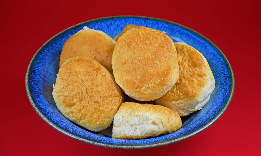 A blue bowl filled with biscuits on top of a red table