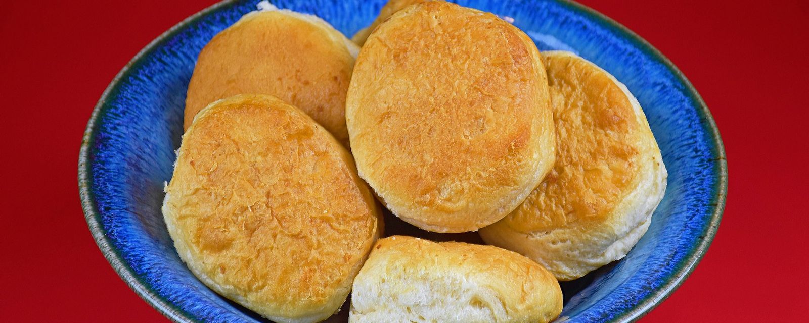 A blue bowl filled with biscuits on top of a red table