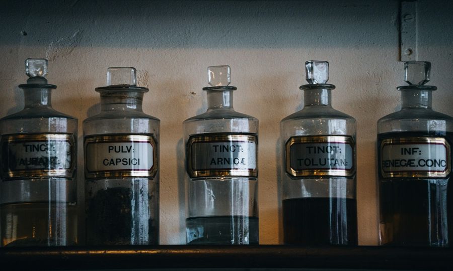 Five vintage apothecary bottles with labels on shelf