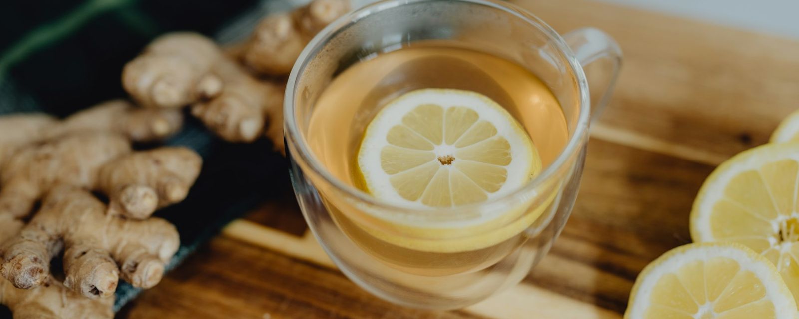 A cup of tea with lemon and ginger on a cutting board