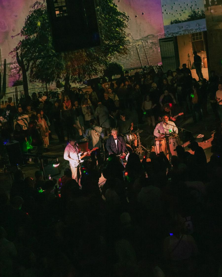 Band performs in a courtyard-like space at night, viewed from above the crowd.