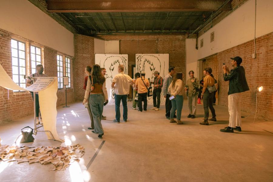 Visitors gather inside a gallery to view a large-scale installation and hanging artworks.