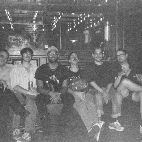 Black and white, grainy photograph of the band Los Esplifs istting in a bar or nightclub.