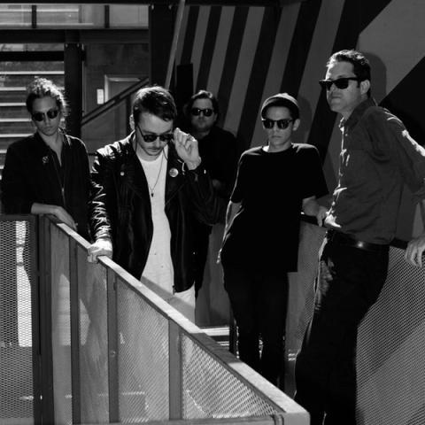Musical group Destruction Unit pictured standing on a staircase, photographed in black and white from below.