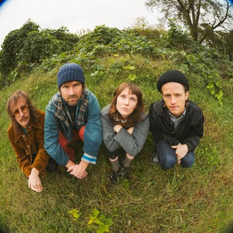 Fisheye distorted photograph of the band Laney Jones and the Spirits sitting in a grassy area by Rachel Weber