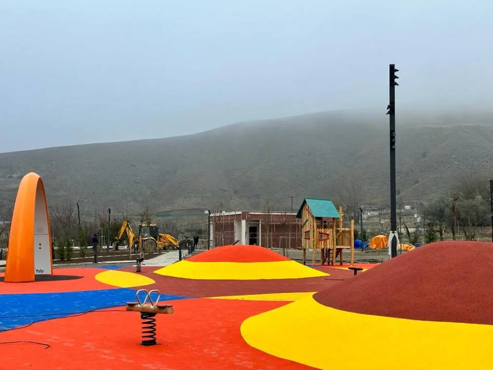 Kırmızı, sarı ve turuncu dökme kauçuk zeminli park ve ahşap oyun evi