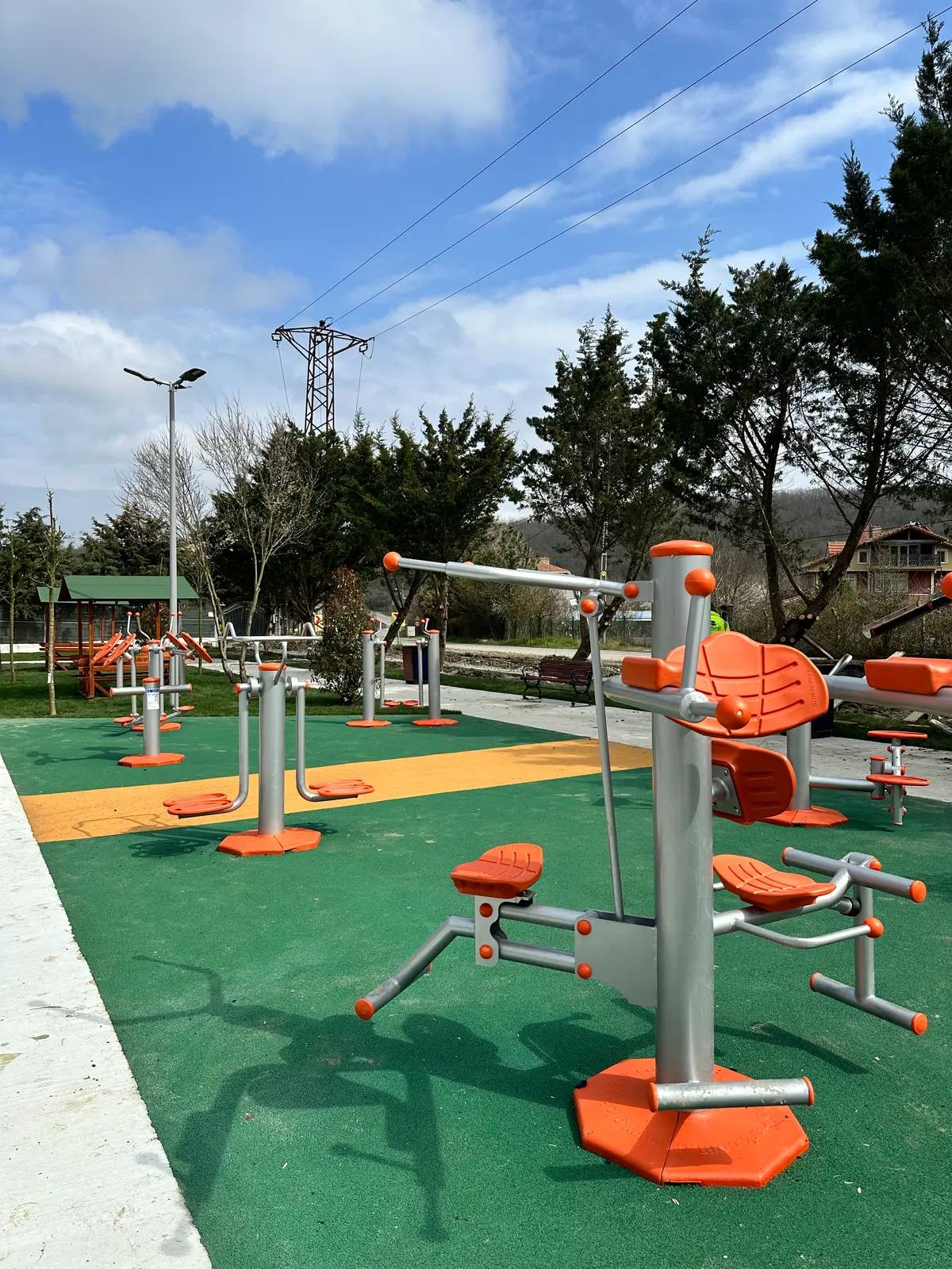 Yeşil kauçuk zemin üzerinde turuncu açık alan fitness ekipmanları