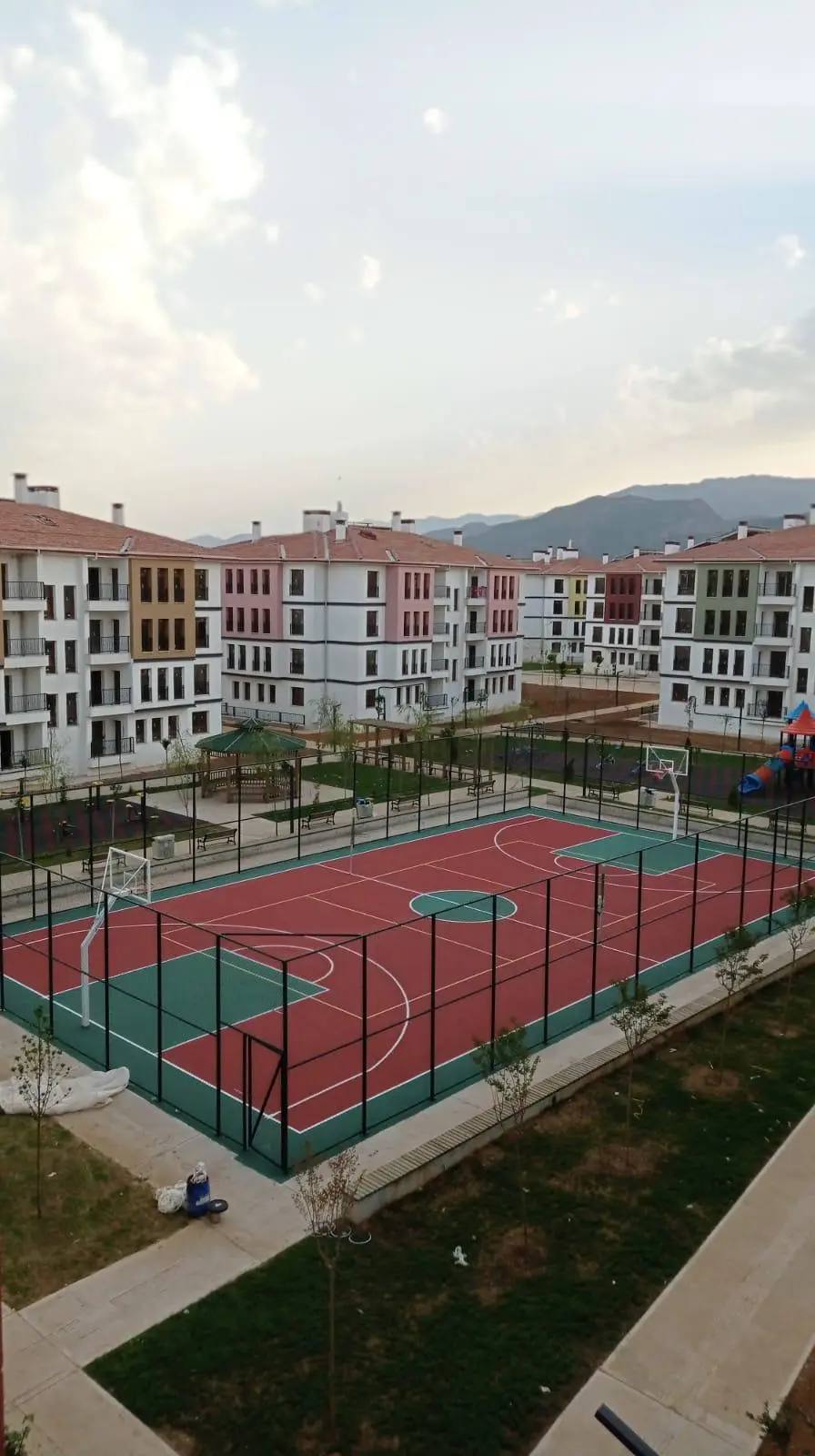 Konut sitesi içinde kırmızı ve yeşil akrilik zeminli spor sahası