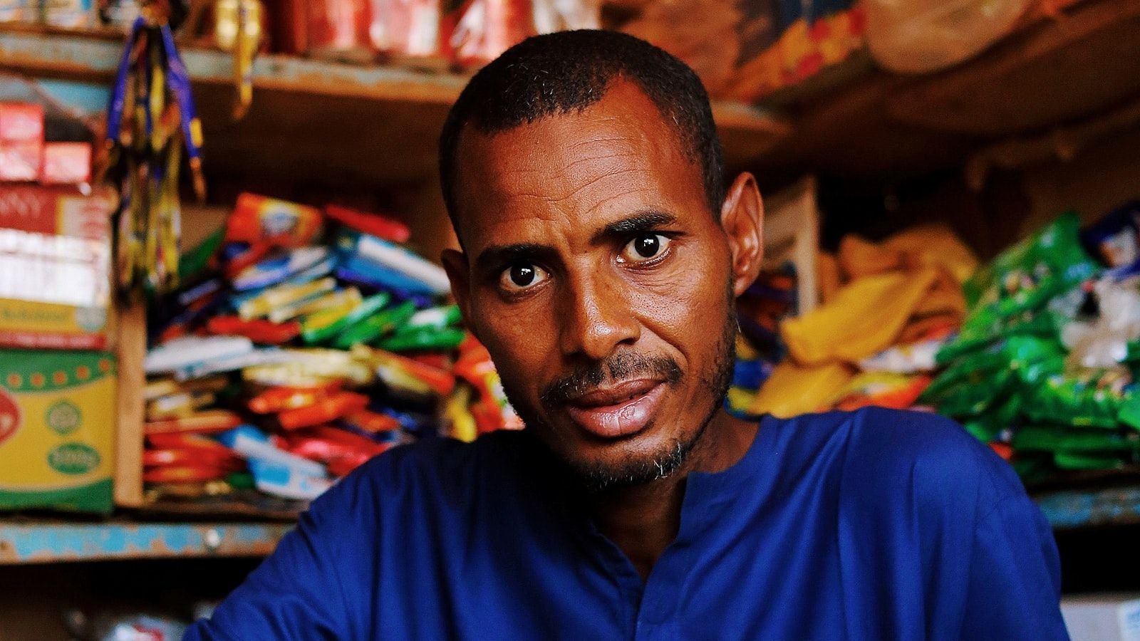 Shop owner surrounded by stocked shelves in his store