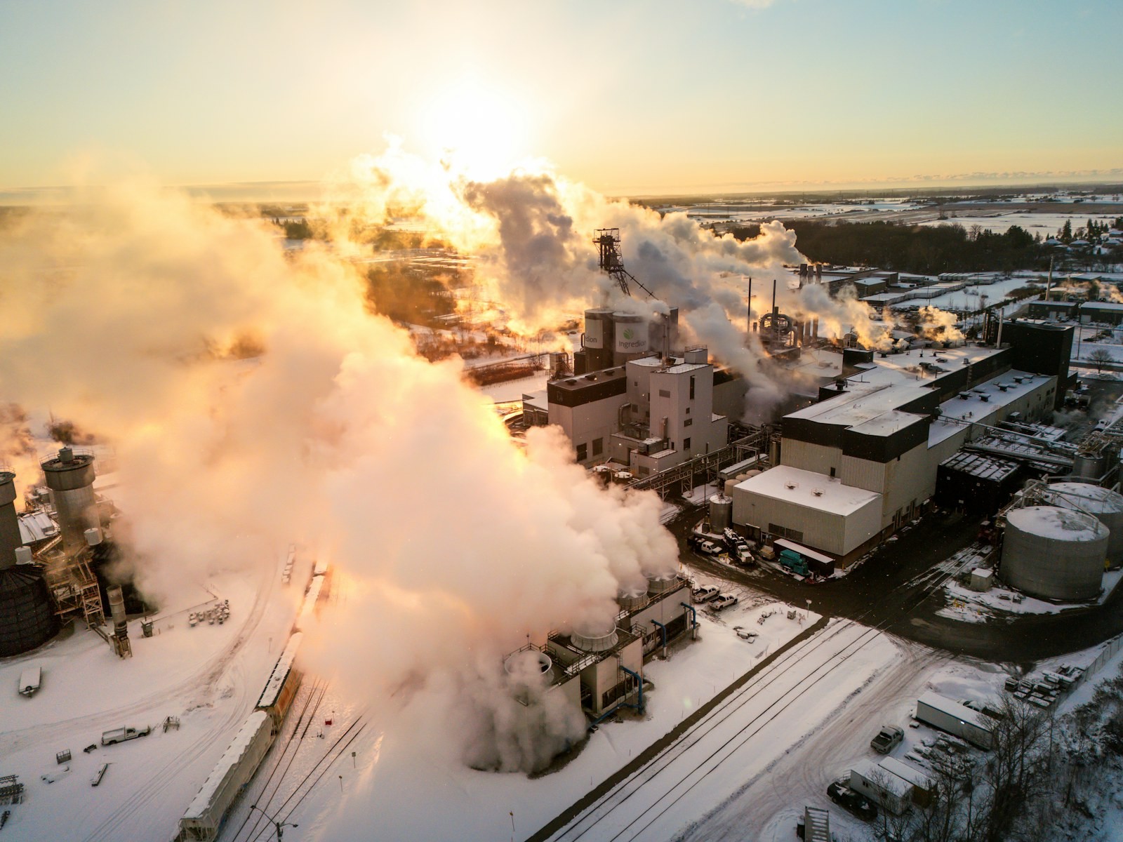 An industrial plant at first light, steam rising from its stacks