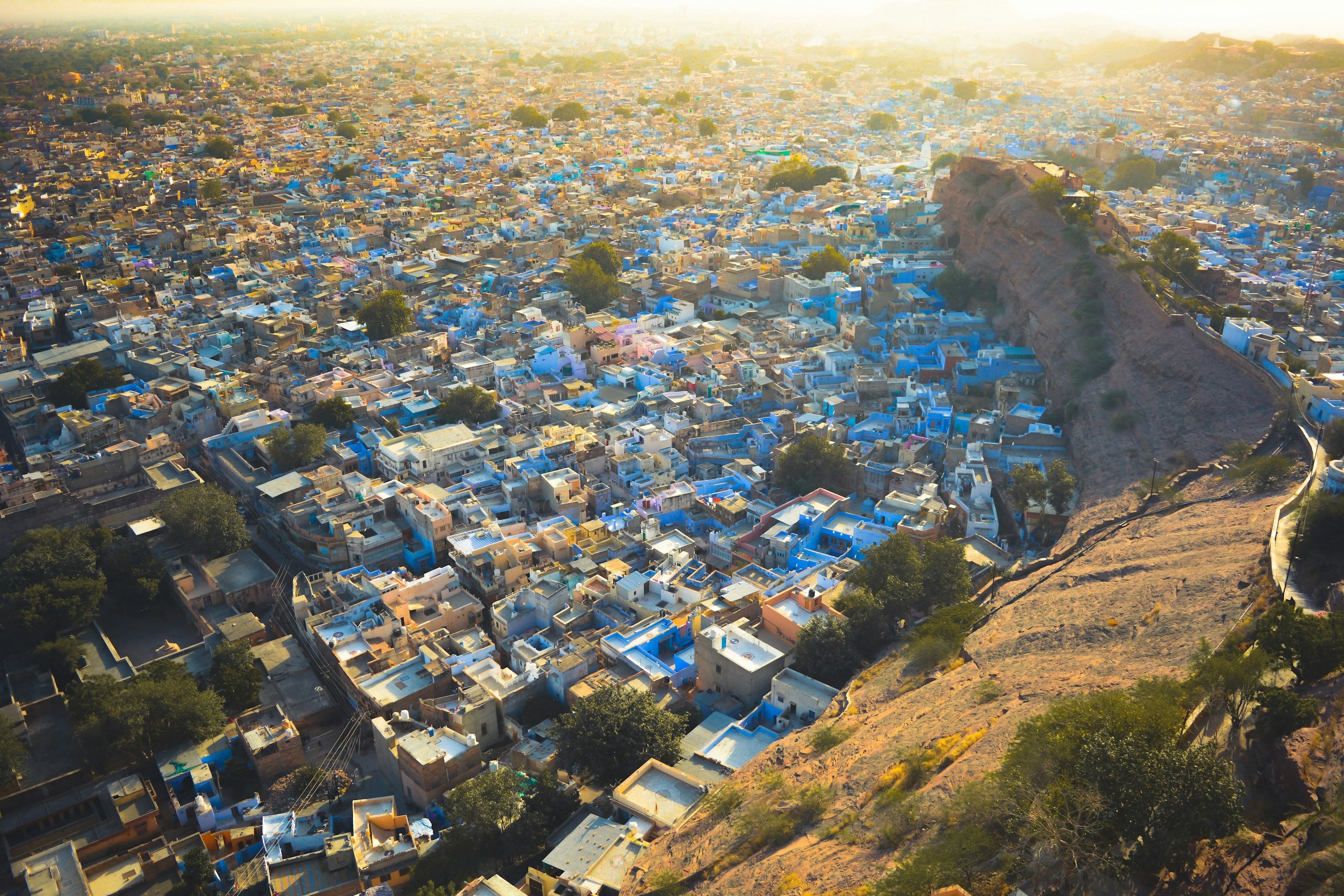 Densely built blue-washed old town at the foot of a rock ridge, from the air
