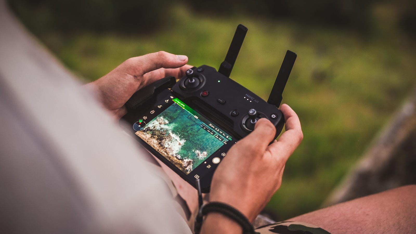 Hands on a drone controller, the terrain image on the display