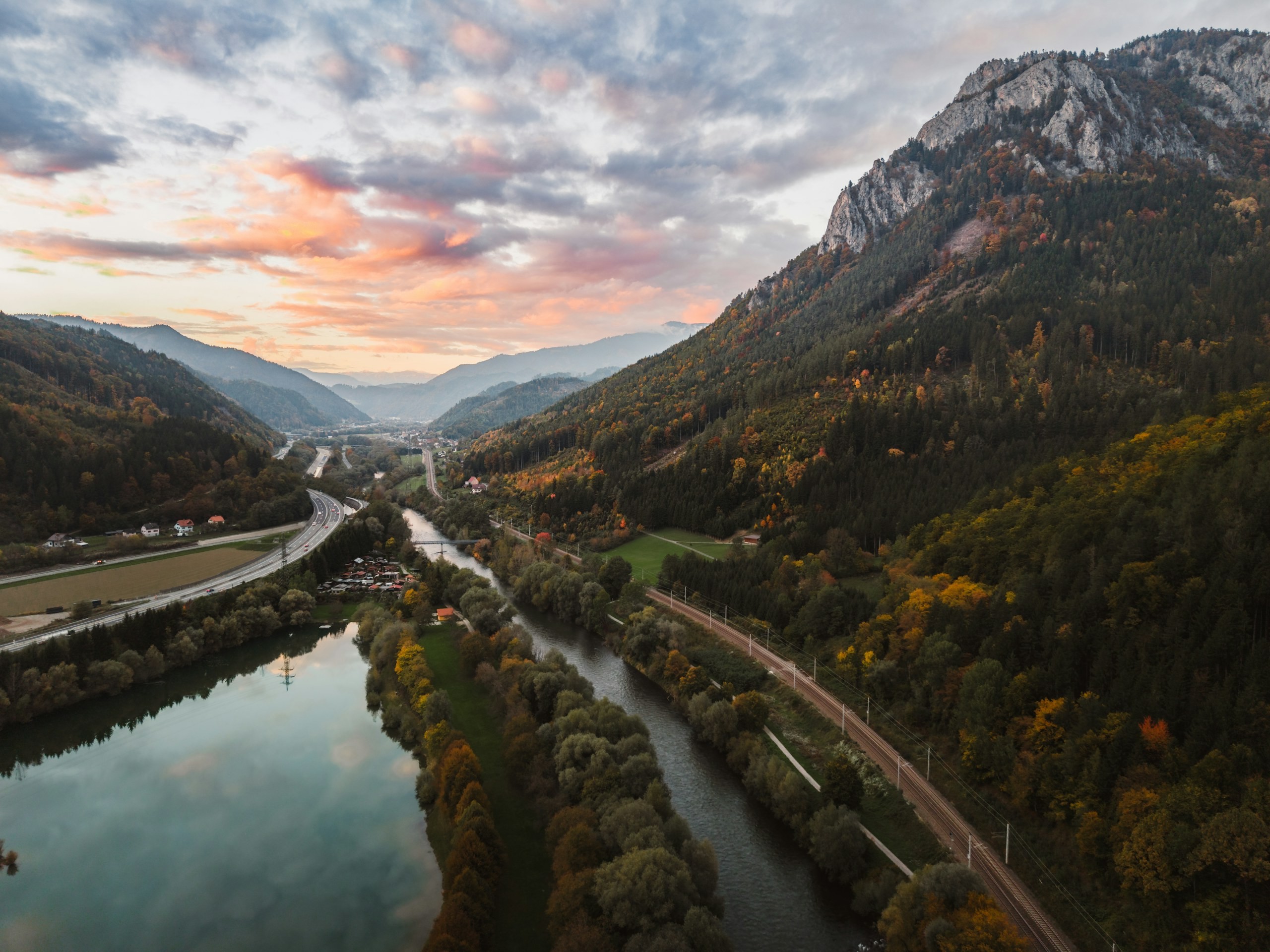 River valley carrying a road and a railway, mountain ranges in morning light