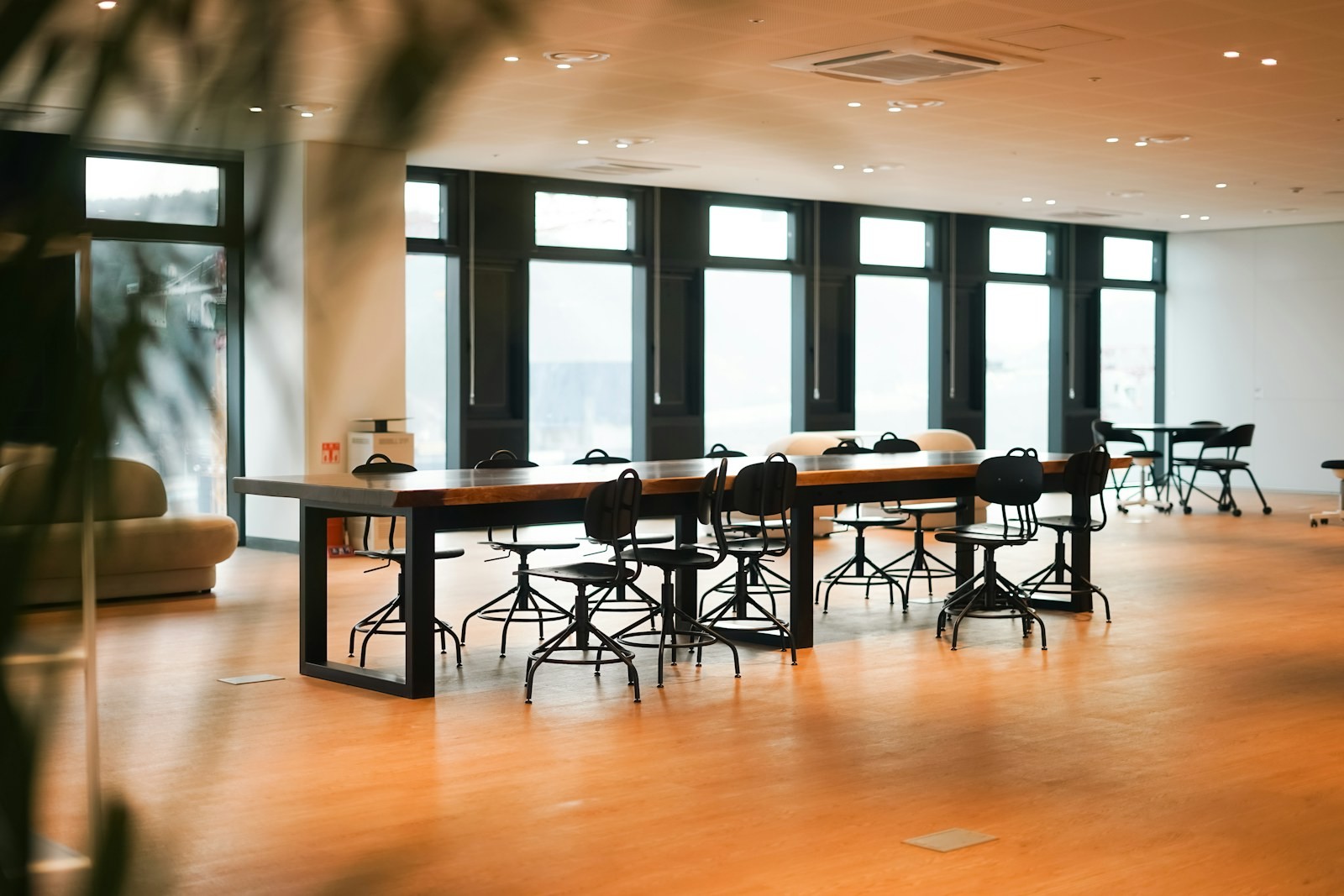 Open work area with a light wooden floor and long tables