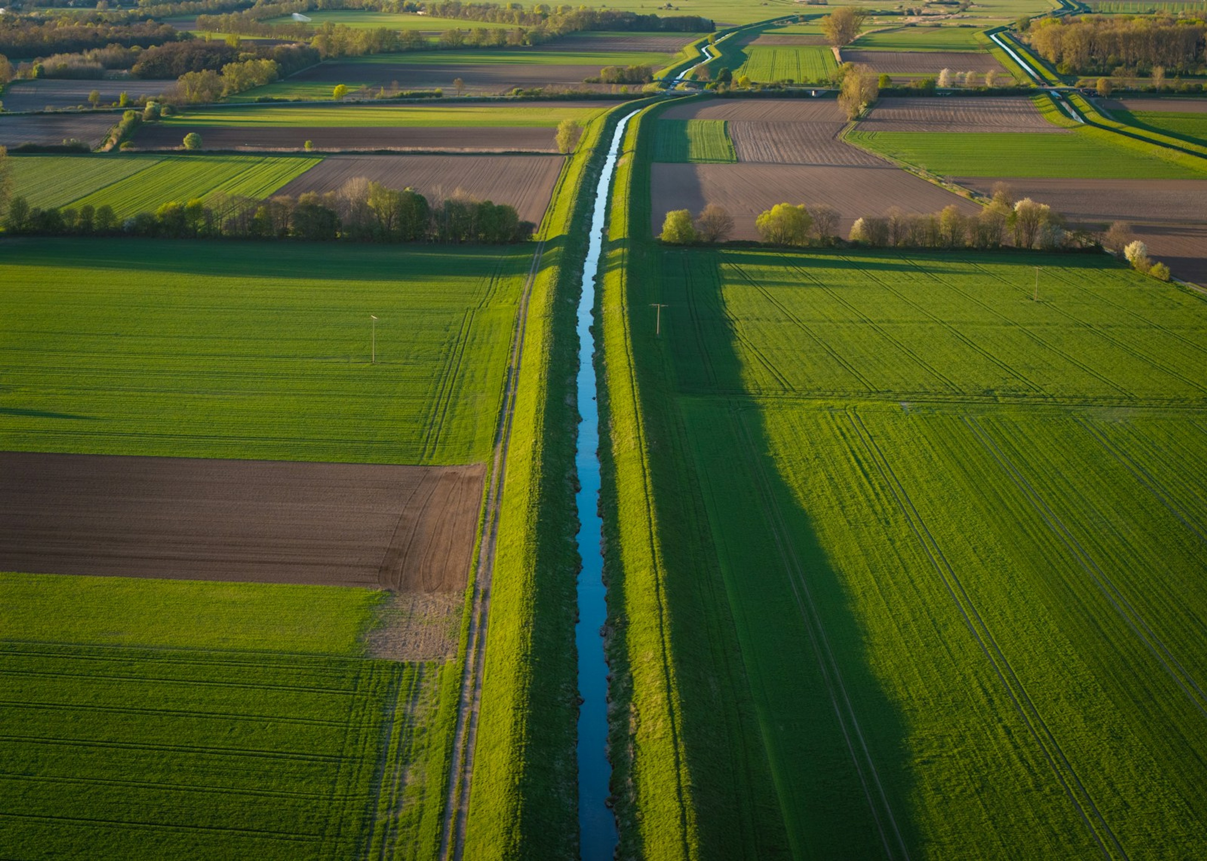 An irrigation canal running diagonally through cultivated fields, seen from the air
